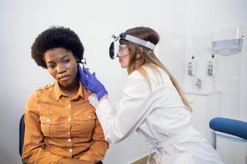 Doctor using ENT supplies and devices for an ear examination on a patient in a clinic setting.