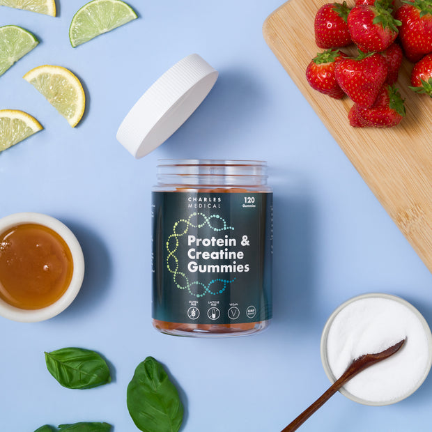 Vegan protein creatine gummies jar surrounded by fresh ingredients like lime slices, strawberries, honey, and basil on a wooden board.
