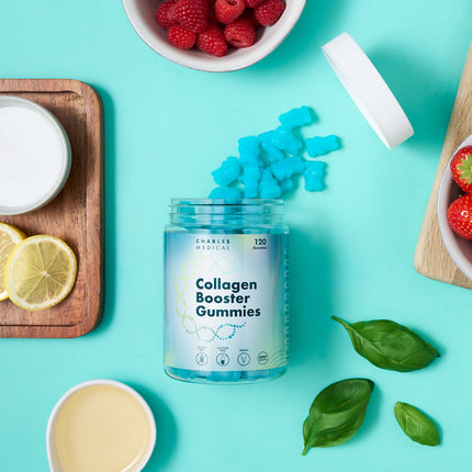Vegan collagen booster gummies jar surrounded by fruits and mint on a turquoise background.