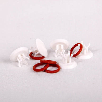 White plastic clips with red rubber bands on a light gray background