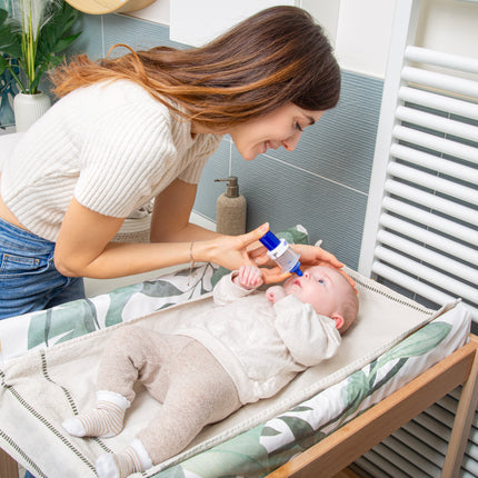 Mother using Rhino Clear Nasal Aspirator to gently relieve baby's nasal congestion on changing table.
