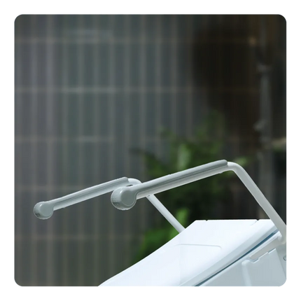 A close-up of a white plastic grab handle mounted on a white toilet tank, set against a blurred gray tiled bathroom background.