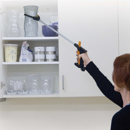 Person using Handy Grabber magnetic reach tool to retrieve a vase from a high shelf in the kitchen