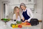 Two women cooking in a kitchen with the iGo2 Portable Oxygen Concentrator on the counter